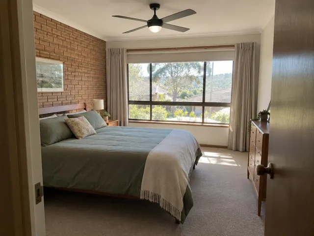 Ceiling fan in a bedroom with brick feature wall and large window in Mount Colah